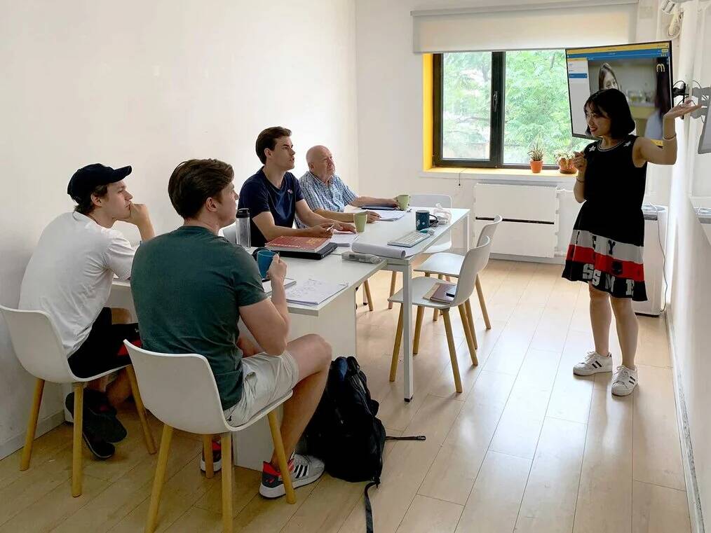 Four men sit in a classroom and look at a teacher.