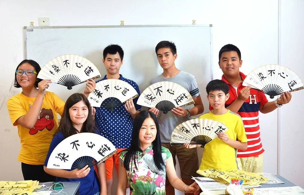Children hold up painted fans.