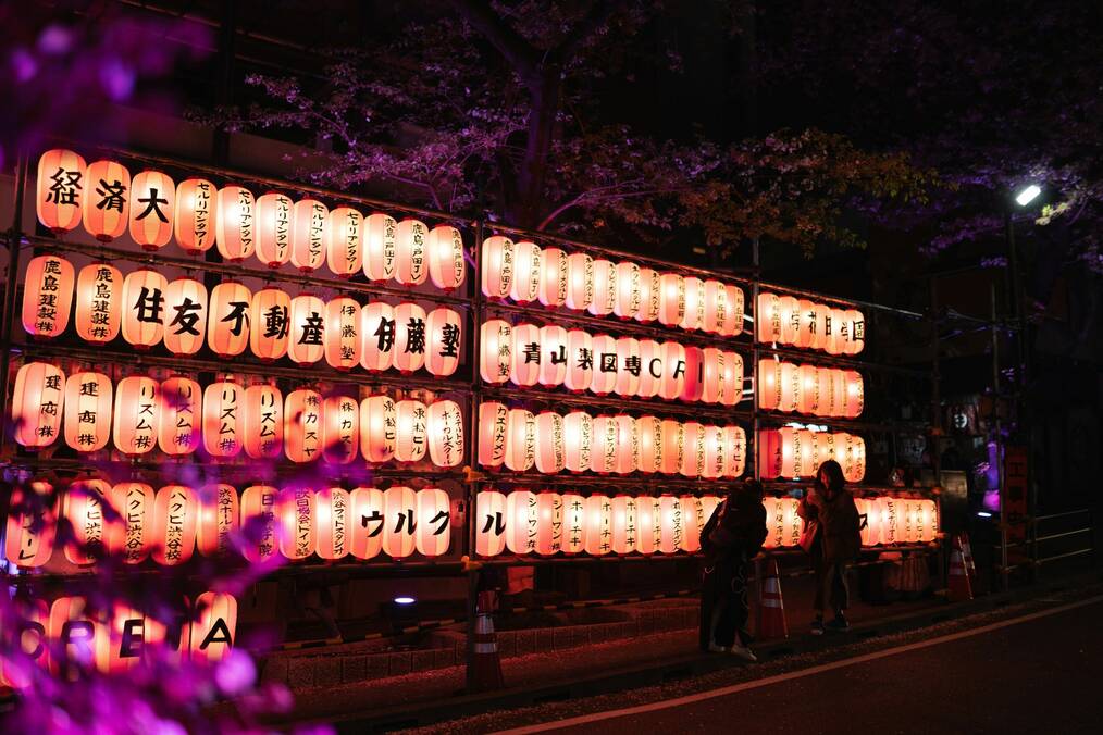 People stand by illuminated lanterns at night.