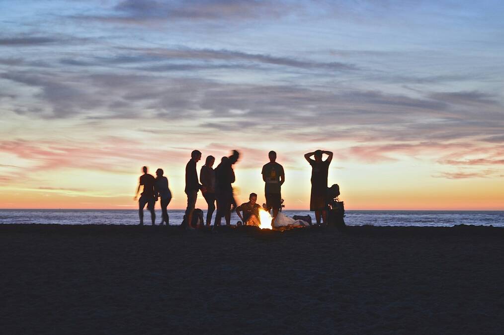A group of friends at a campfire on the beach