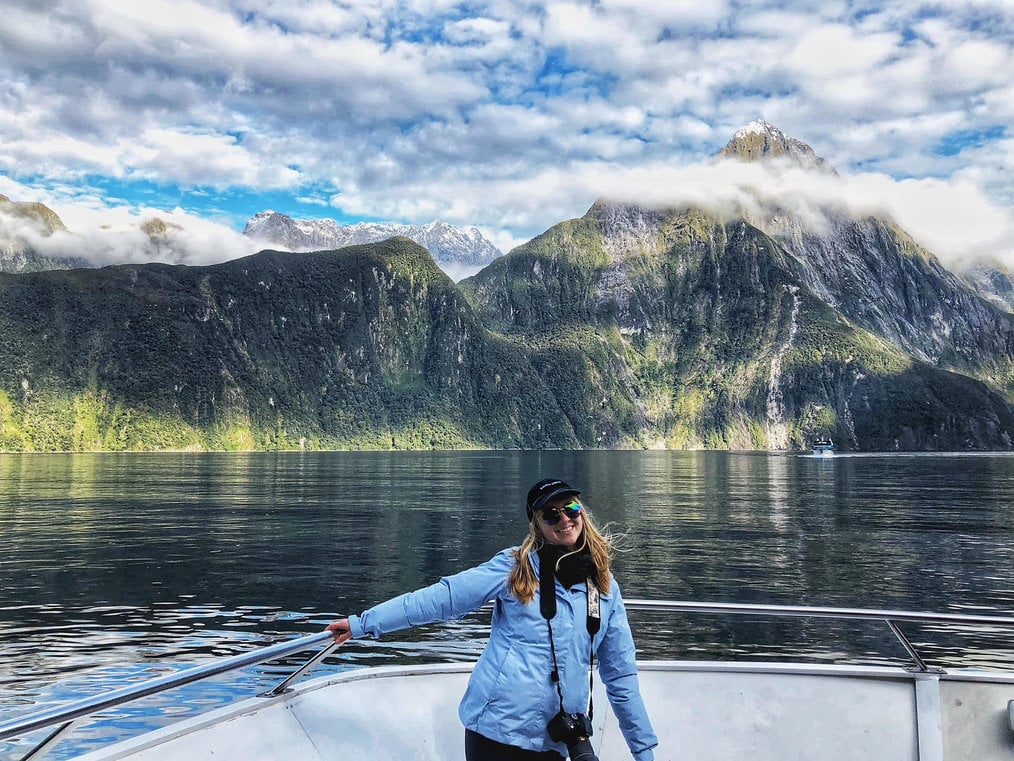 A woman in a coat stands on a boat.