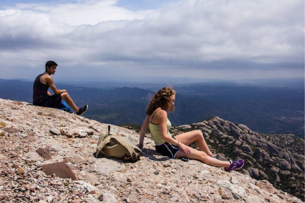 Two students on a cliff looking at the Spanish landscape