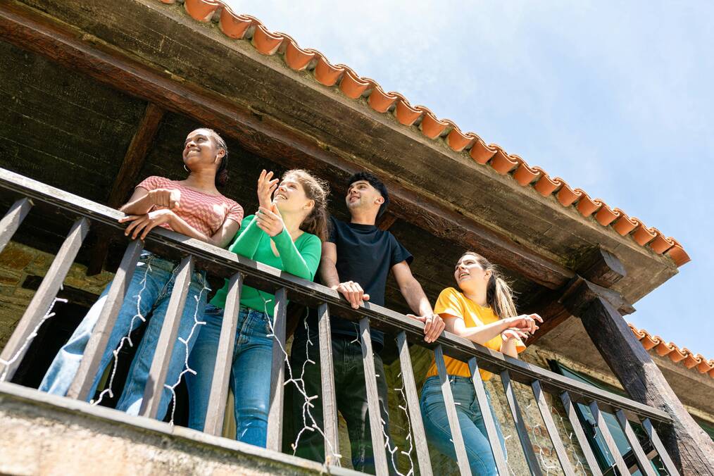 Four friends stand on a balcony.