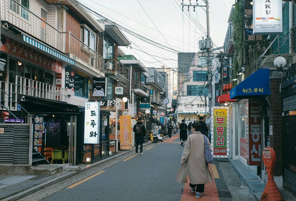 People walk down a shopping street in Seoul.