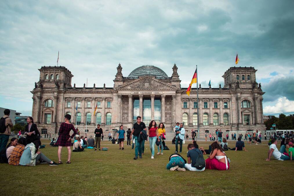 People sit on the grass in front of a building in Germany.