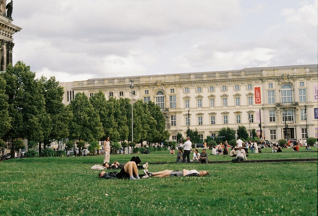 Photo by Korkut Mamet People lay on the grass outside of a building in Germany.