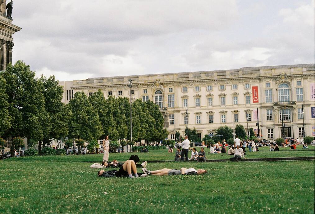 People lay on the grass outside of a building in Germany.