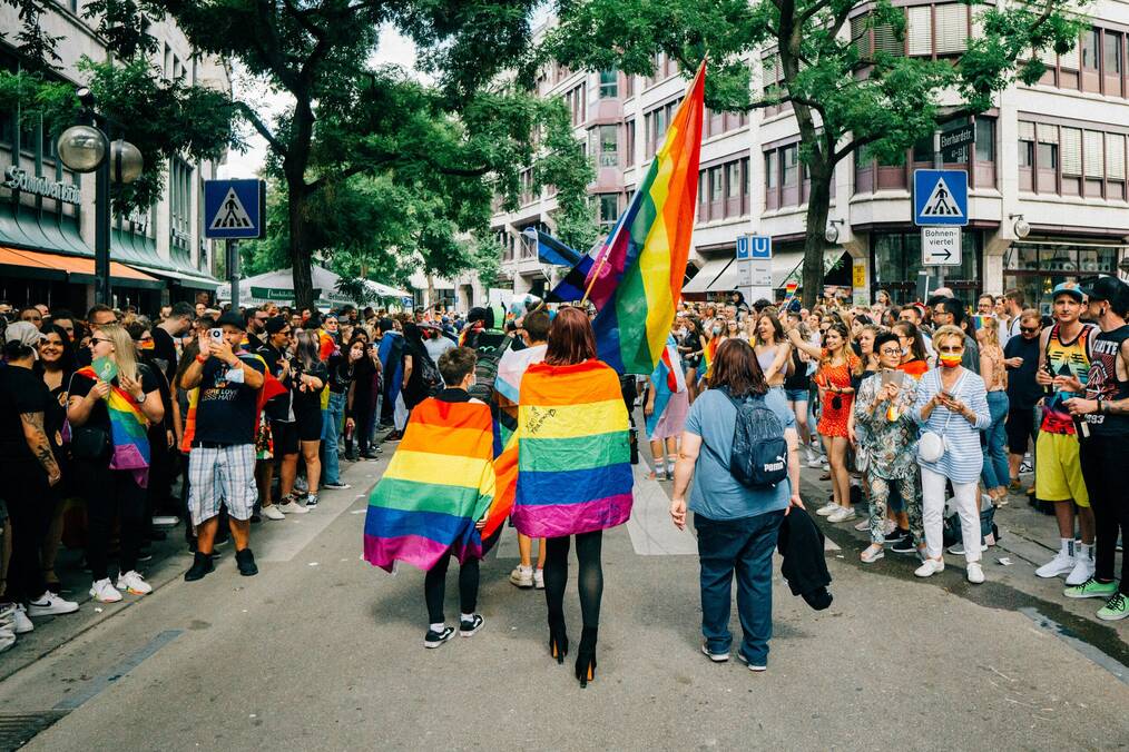 People wearing rainbow flags march in Pride parade in Germany.