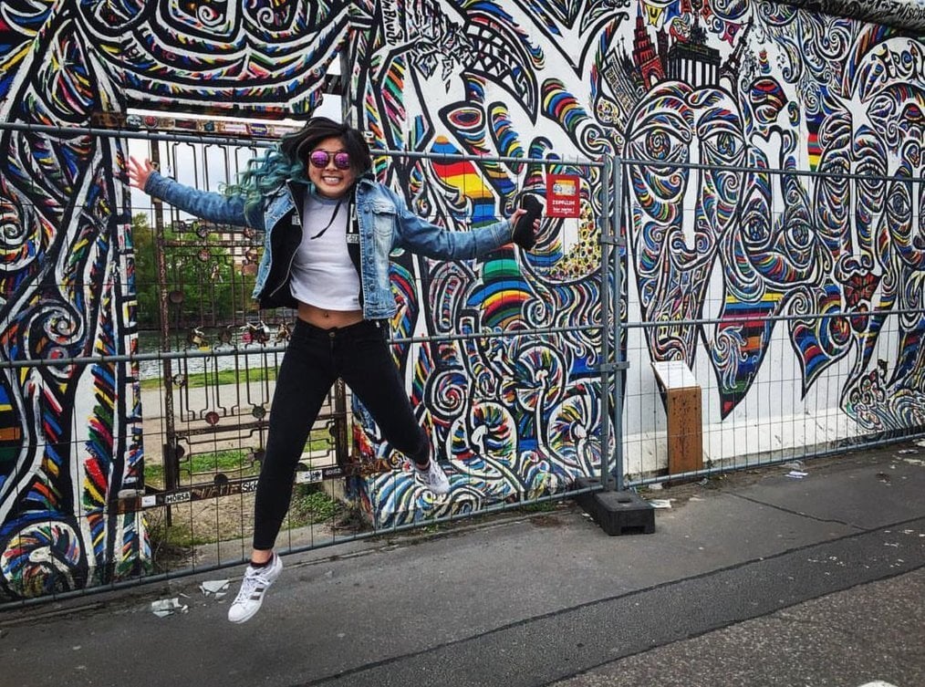 Woman jumping A woman jumps in the air in front of a painted mural.