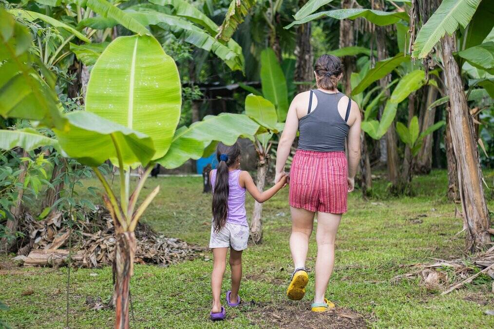A teen girl walks holding hands with a little girl outside.