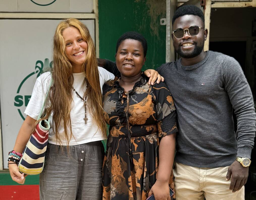 Three people stand together and smile for the camera.