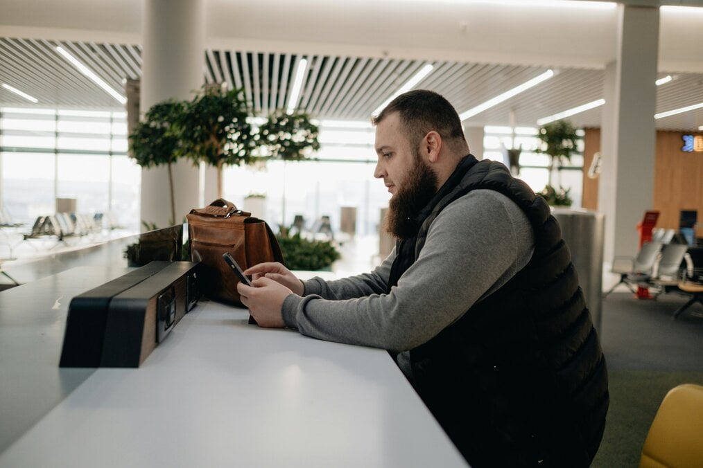 A man looks at his phone in an airport lounge.