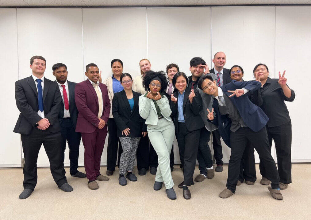 A group of people in business attire pose for a photo.