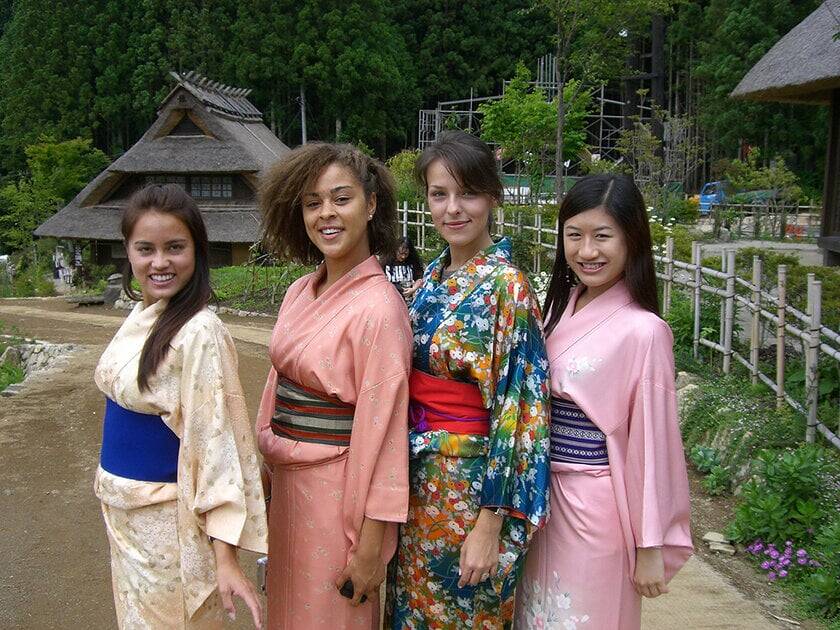 Four women in traditional Japanese clothing pose and smile.