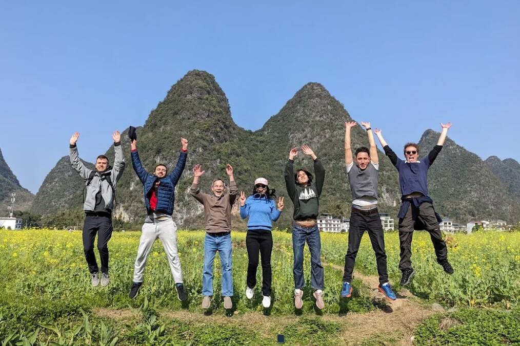 A group of people jumping in the air in front of mountains 