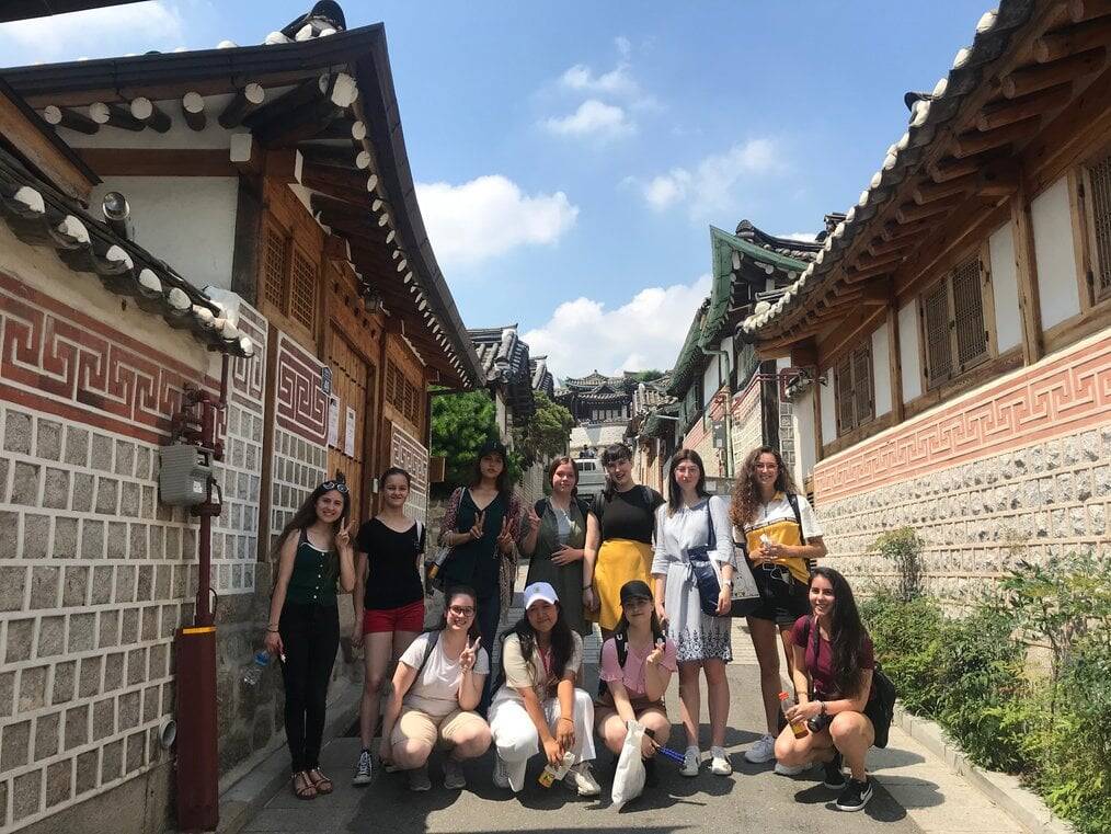 A group of students pose near historic buildings in Korea.