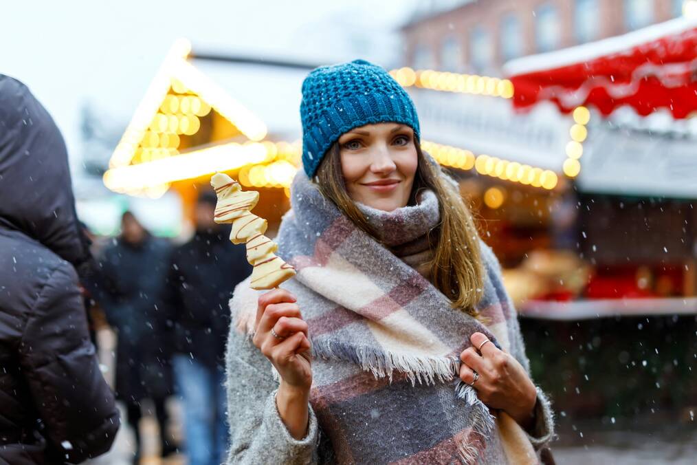 A woman holds a treat at a Christmas market.
