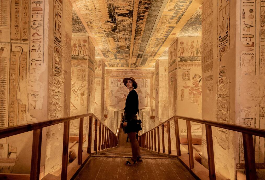 A woman looks at hieroglyphics in a room.