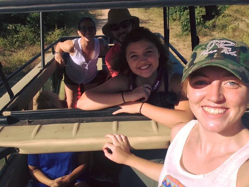 Several people inside of a safari jeep smile.