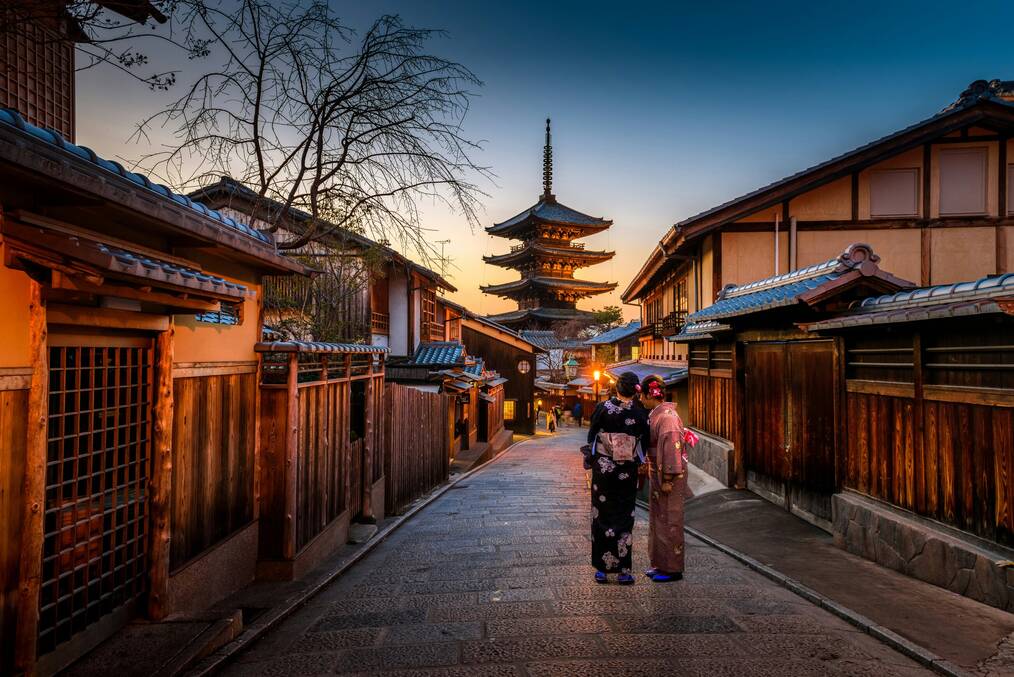 two people in purple and pink kimono standing on the street in Asia