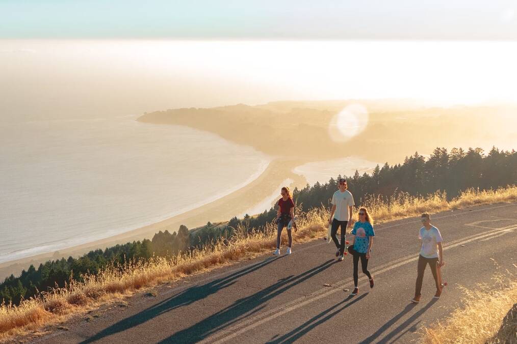 Friends walking alongside a coastal road 