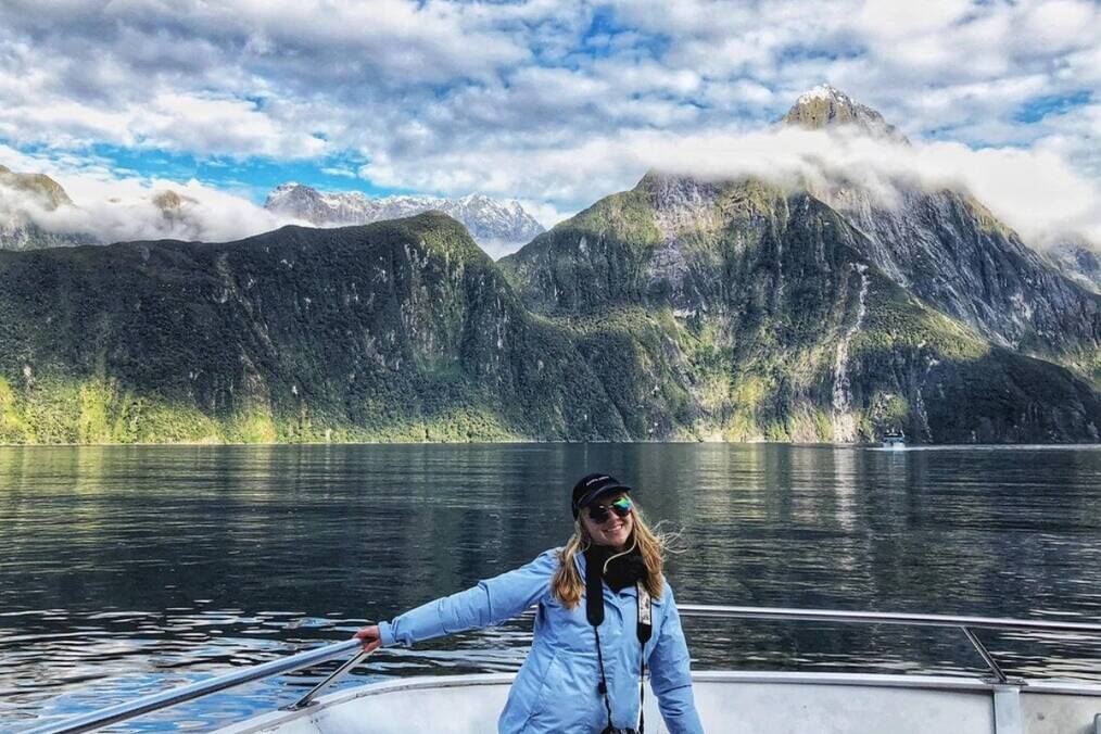 Traveler on a boat smiling in front of water and mountains