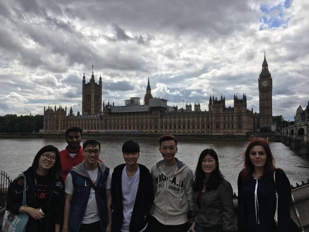 A group of interns stand on a bridge in London with Big Ben in the background.