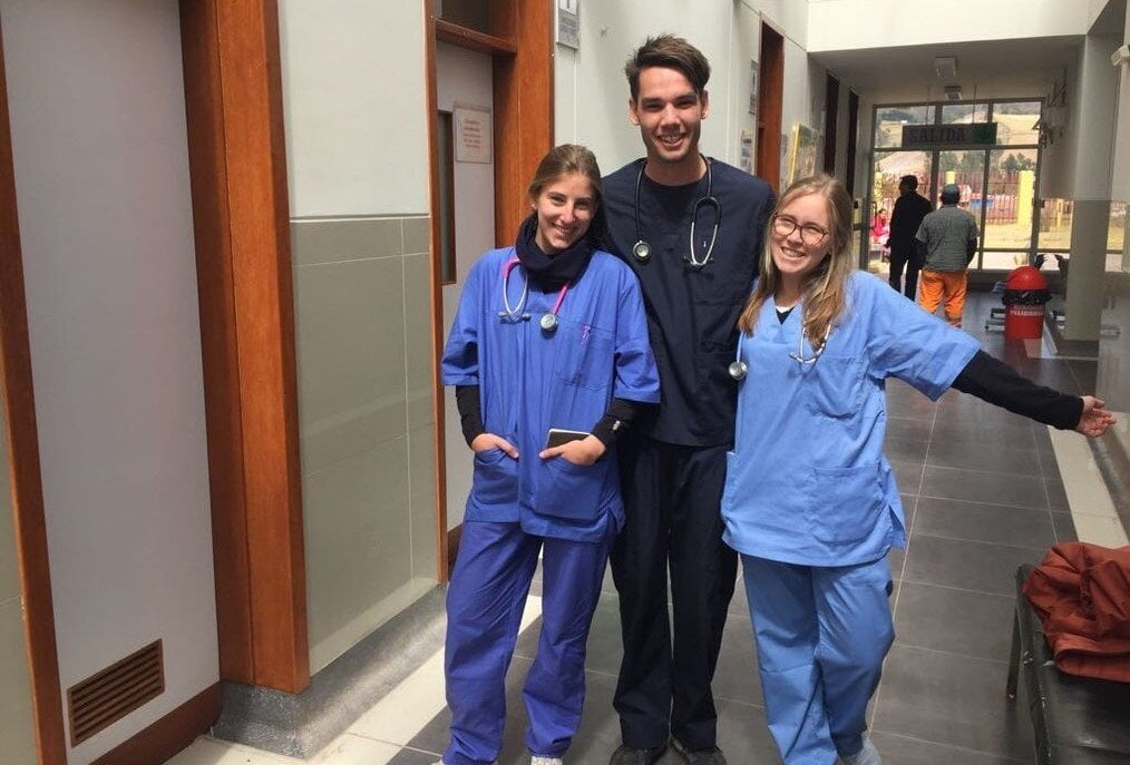 VolSol Three medical volunteers in scrubs pose and smile.