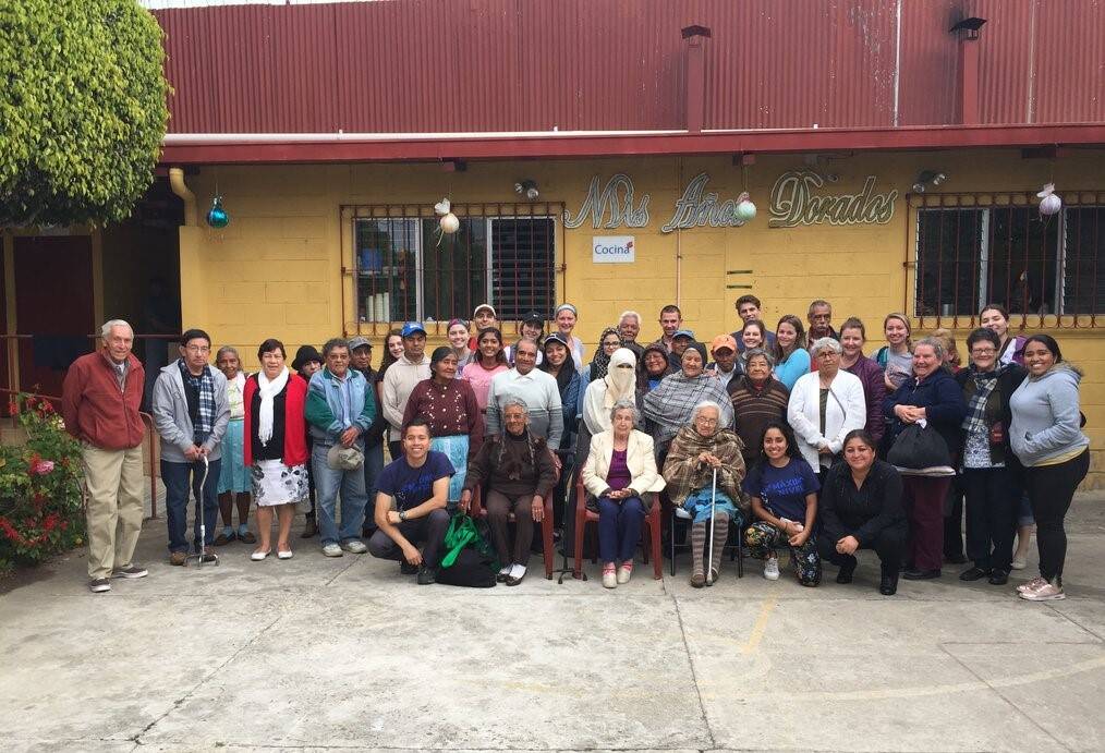A group of volunteers stand together outside of a retirement home.