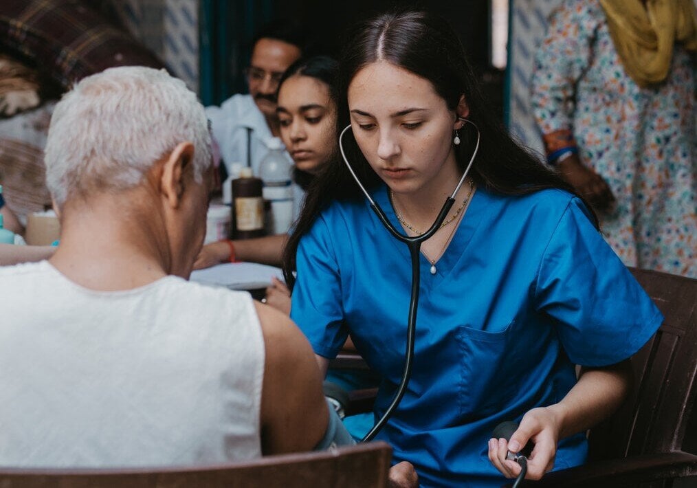 PMGY A woman in scrubs takes a man's blood pressure.