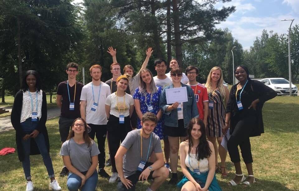 A group of volunteers stand together and smile outside.