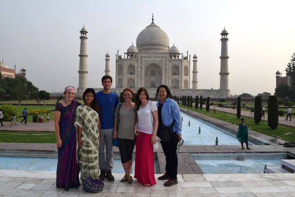 A group of people stand in front of the Taj Mahal.