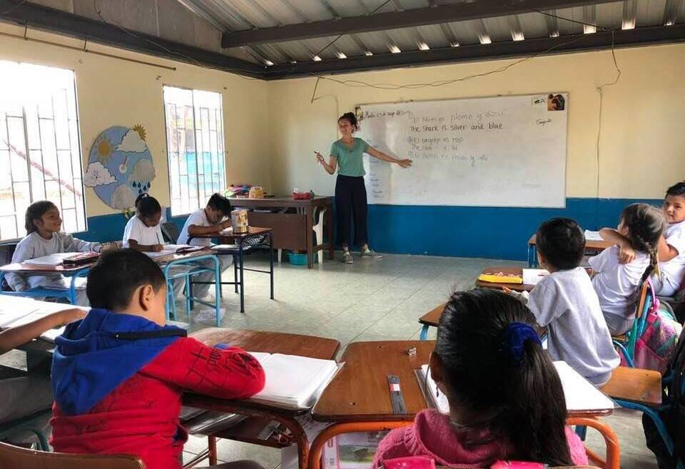 A woman teaches children in a classroom.