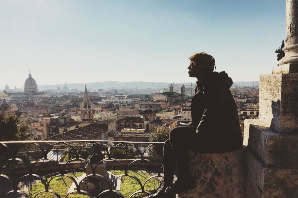 A person sitting on the wall with the backdrop of a Spanish city