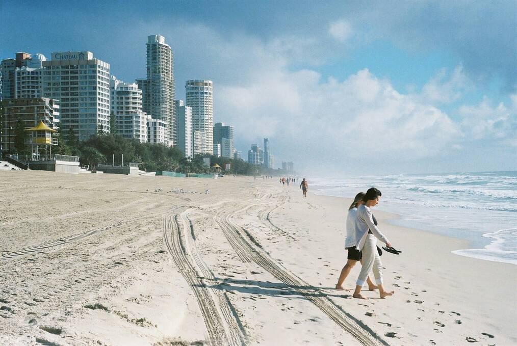 People walk on a white sand beach in Australia.