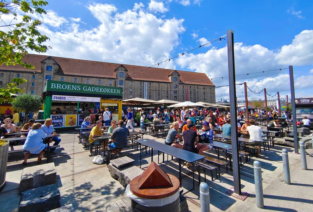 People sit at picnic tables at an outside cafe.