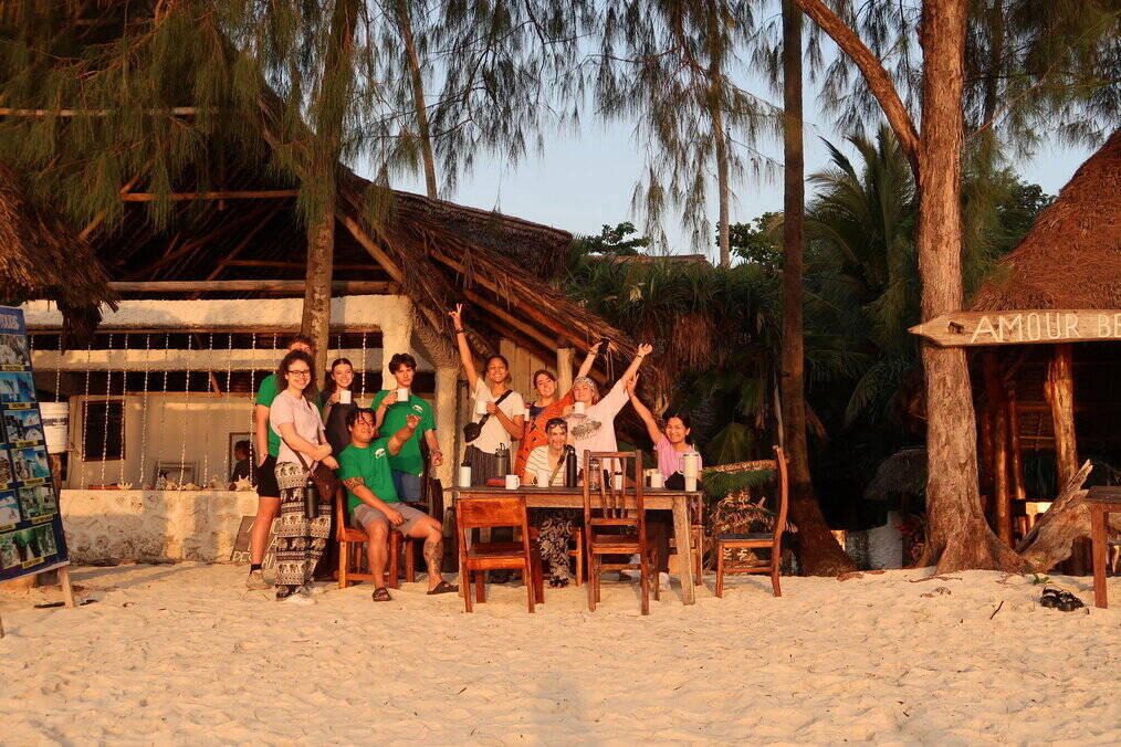 A group of volunteers sit around a table on the beach.