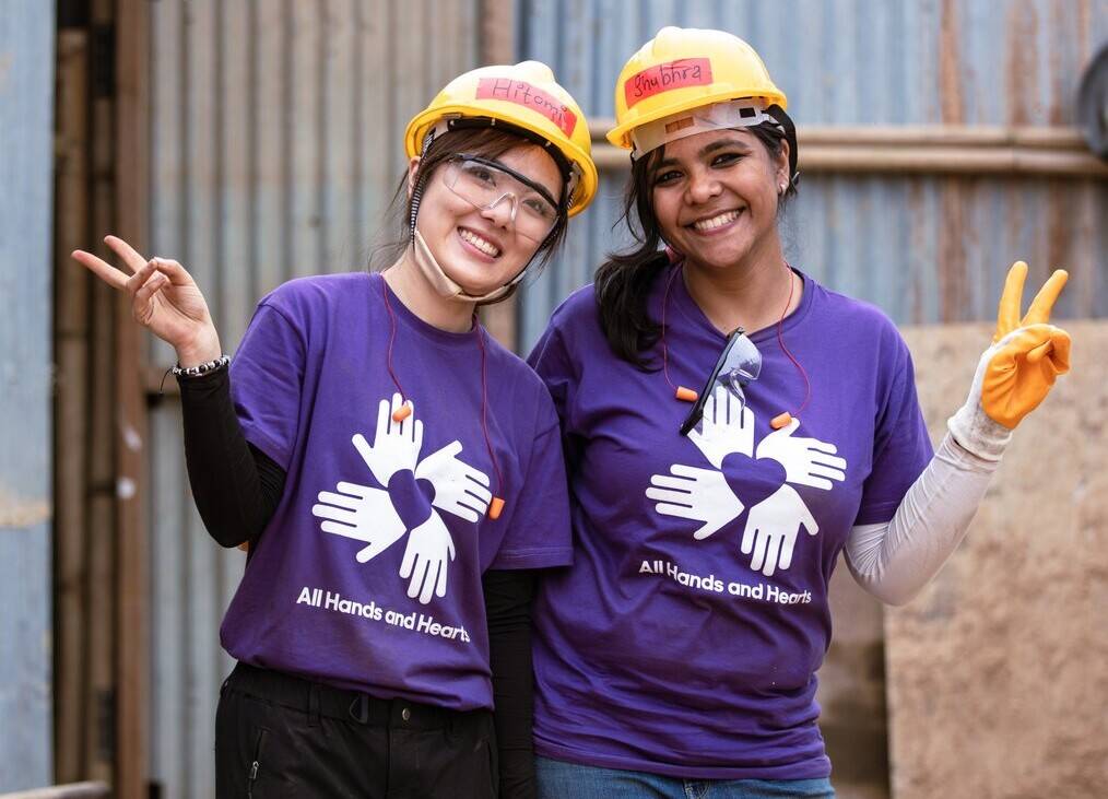 Two volunteers smile and give peace signs.