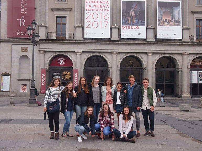 A group of teens pose in front of a museum in Spain.