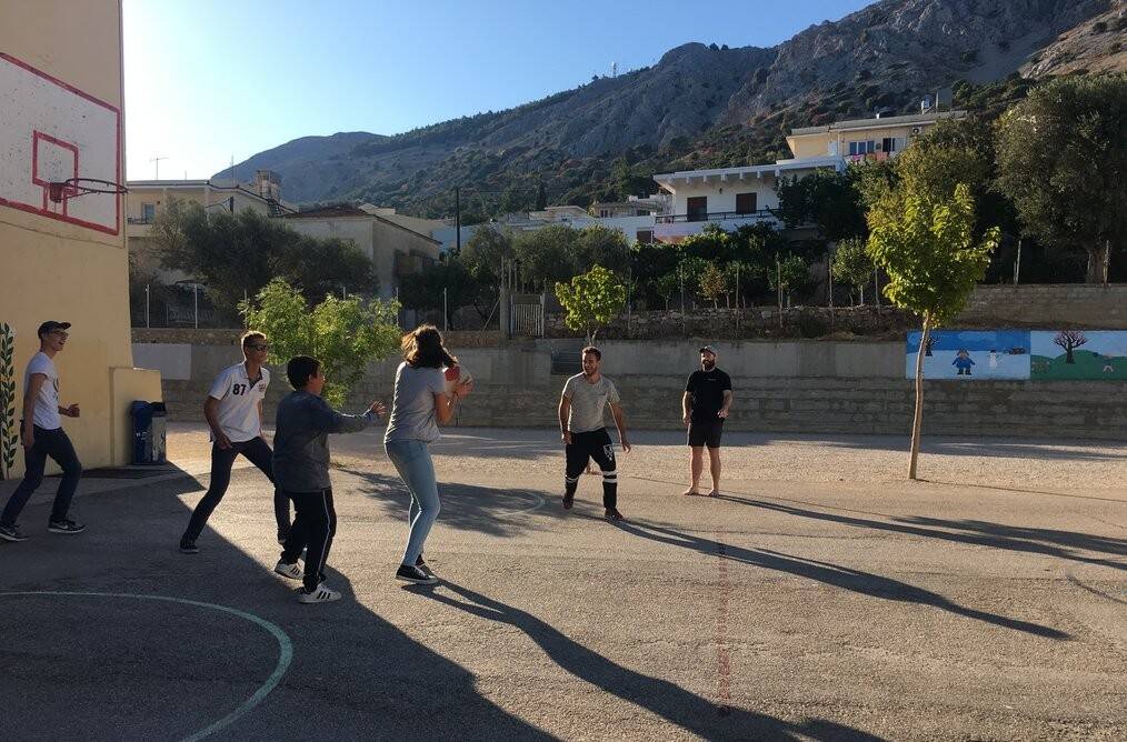A group of young adults play basketball outside.