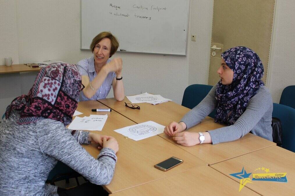 A woman sits a table with two students.