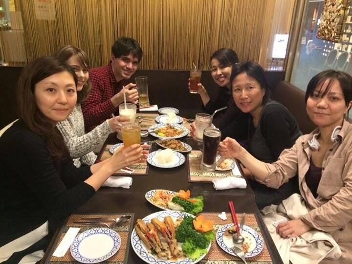 A group of teachers sitting in a restaurant raise their glasses.