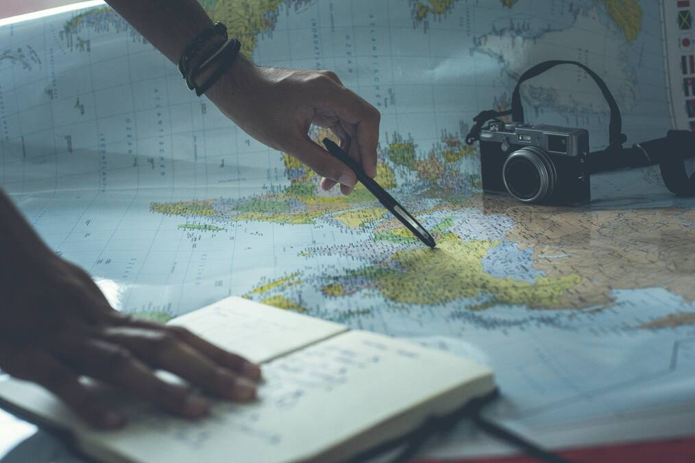 A hand holding a pen points at a place on a map.