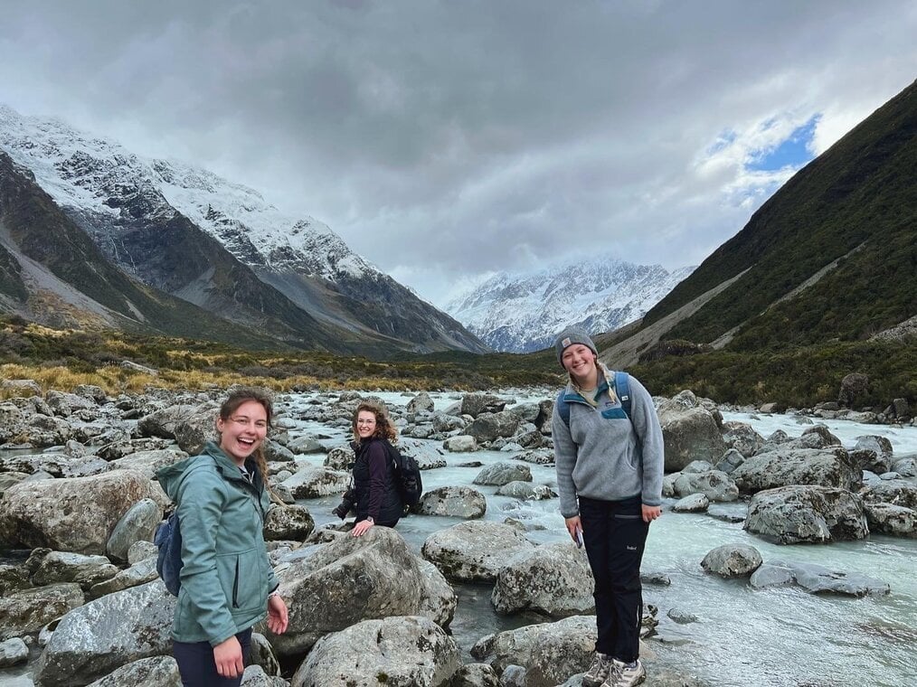 NZ hiking Three women smile with mountains in the background.
