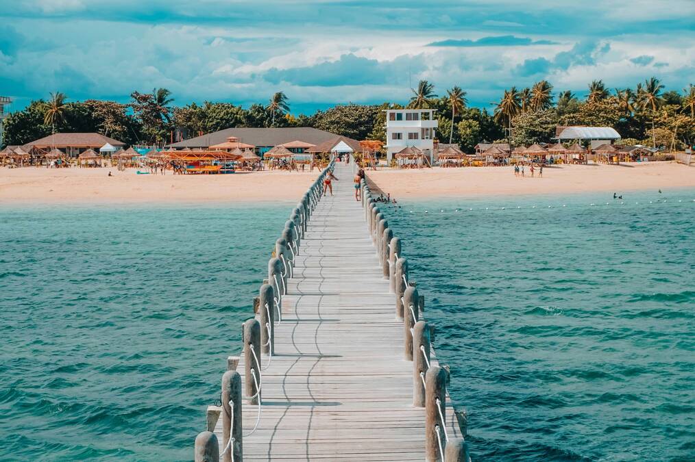 A long boardwalk leads to a sandy beach.