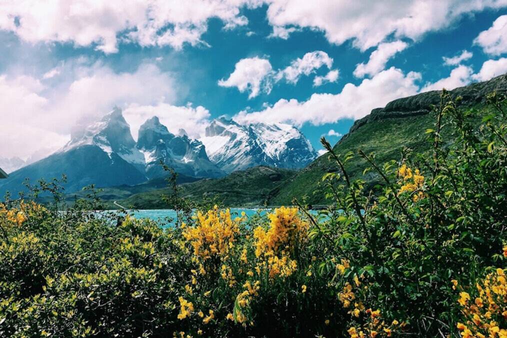 A lake next to mountains under a cloudy sky