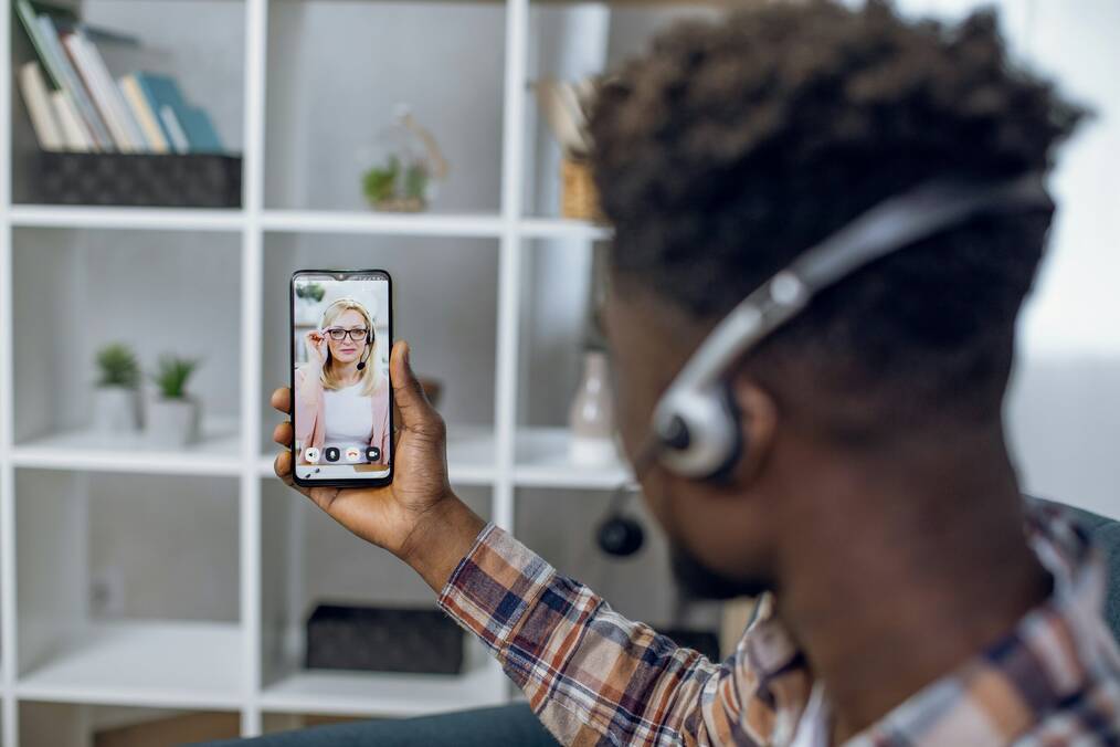 A woman and a man wearing headsets have a video chat on a phone.