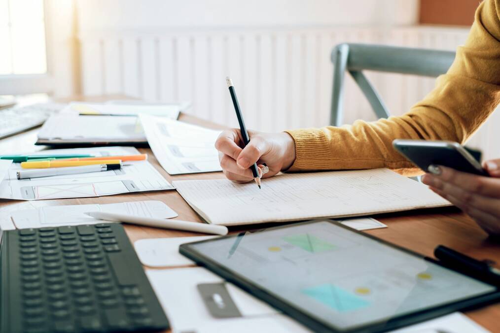 A researching using a tablet and a notebook
