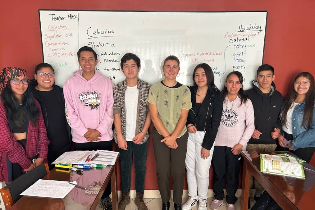 A teacher and their students standing in front of the whiteboard in class