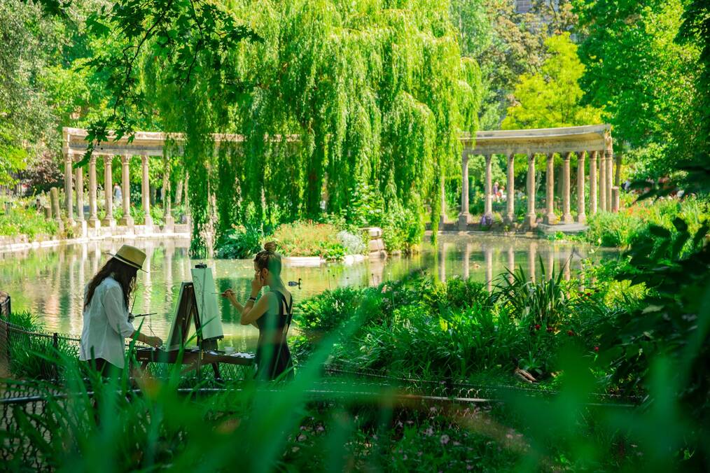 Two artists painting on easels in a garden in Paris, France
